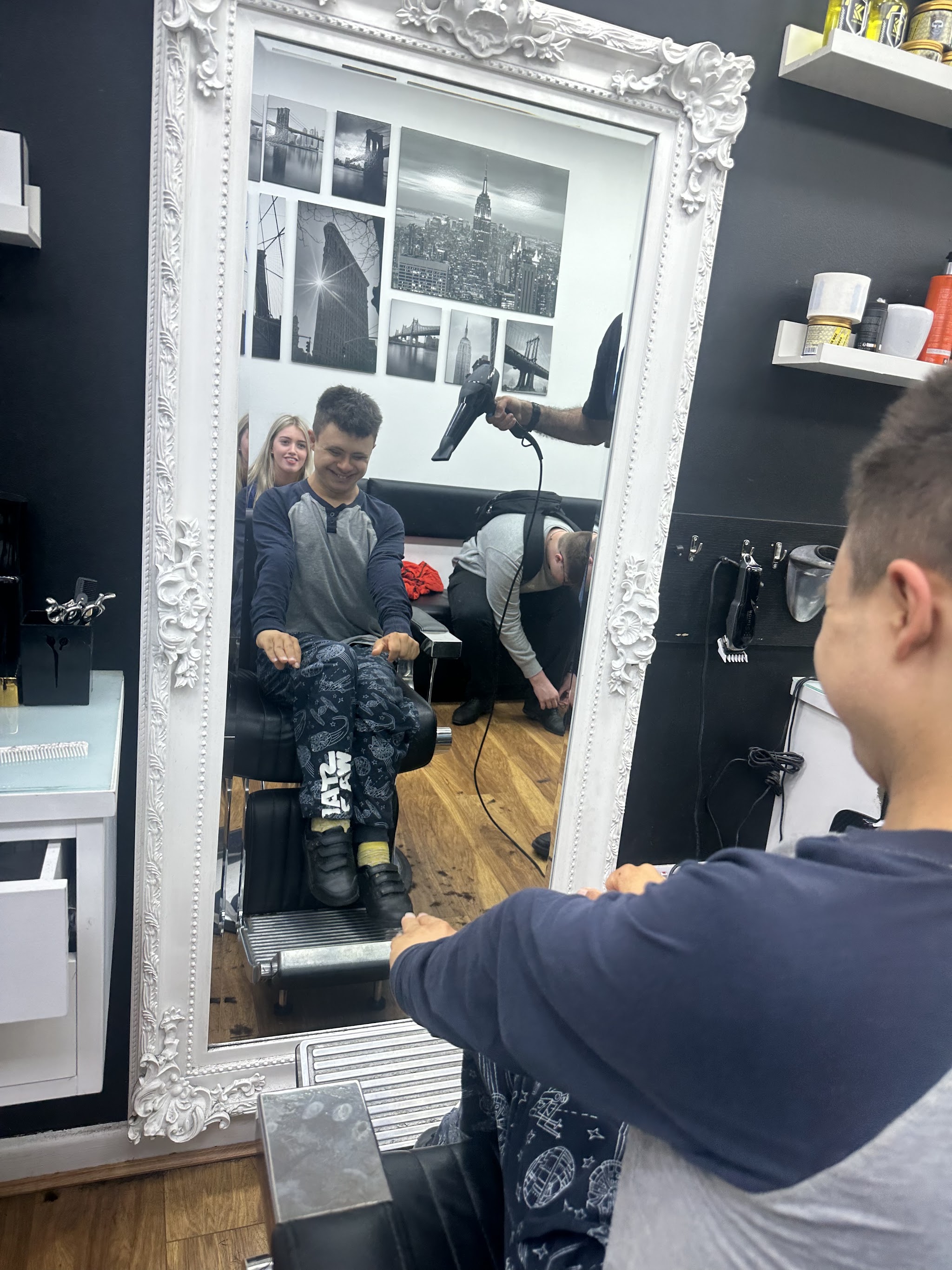 A young customer smiling in the mirror after his haircut